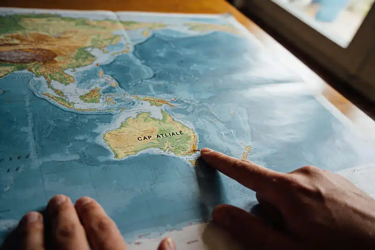 Carte géographique de l'Australie et de l'Asie, doigts pointant l'Australie.