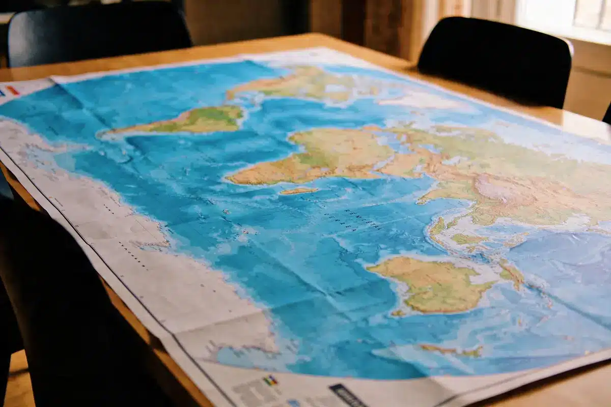Carte du monde étendue sur une table en bois, avec océan et continents visibles.