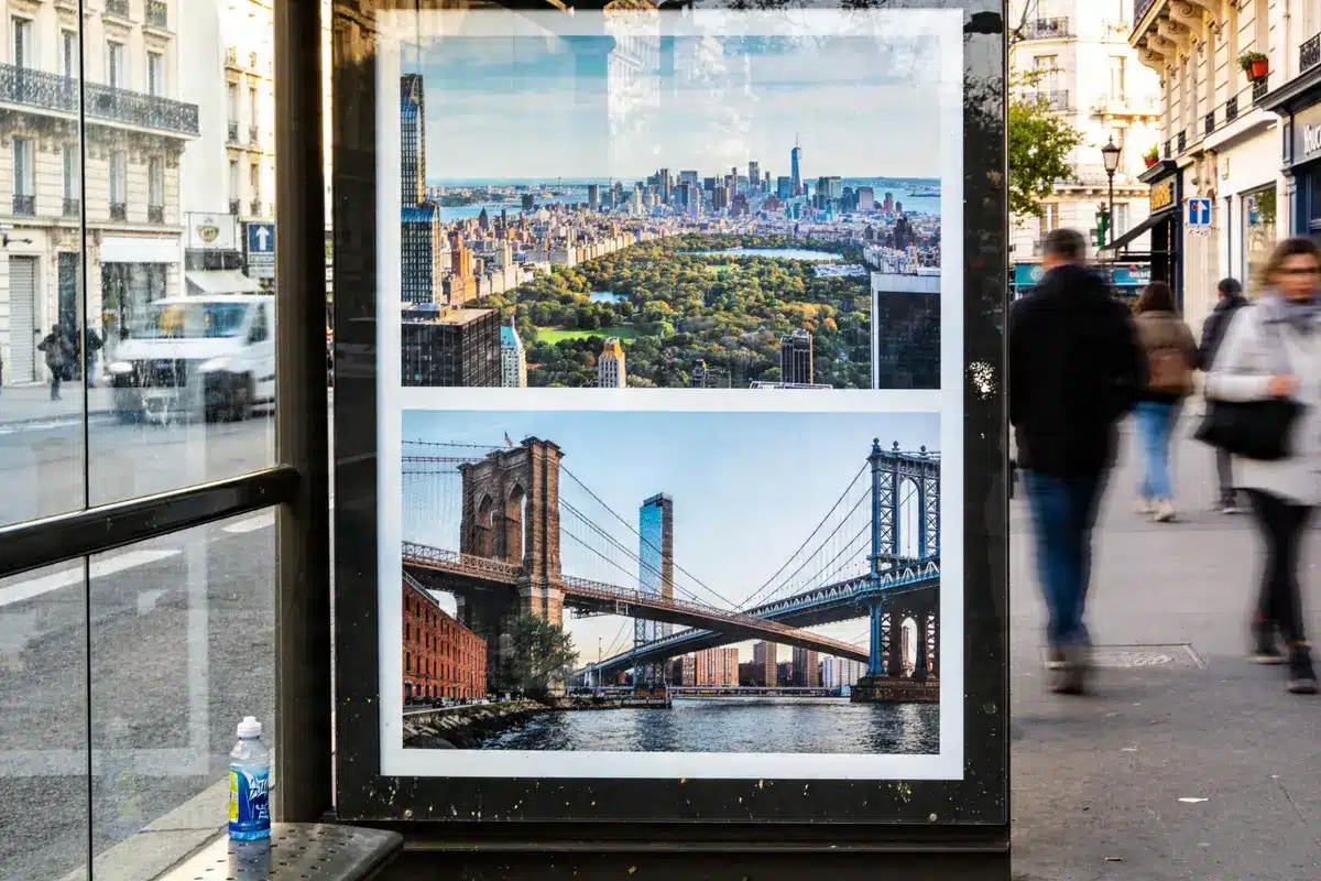 Affiche dans une rue parisienne avec des photos de New York, Central Park et ponts célèbres.