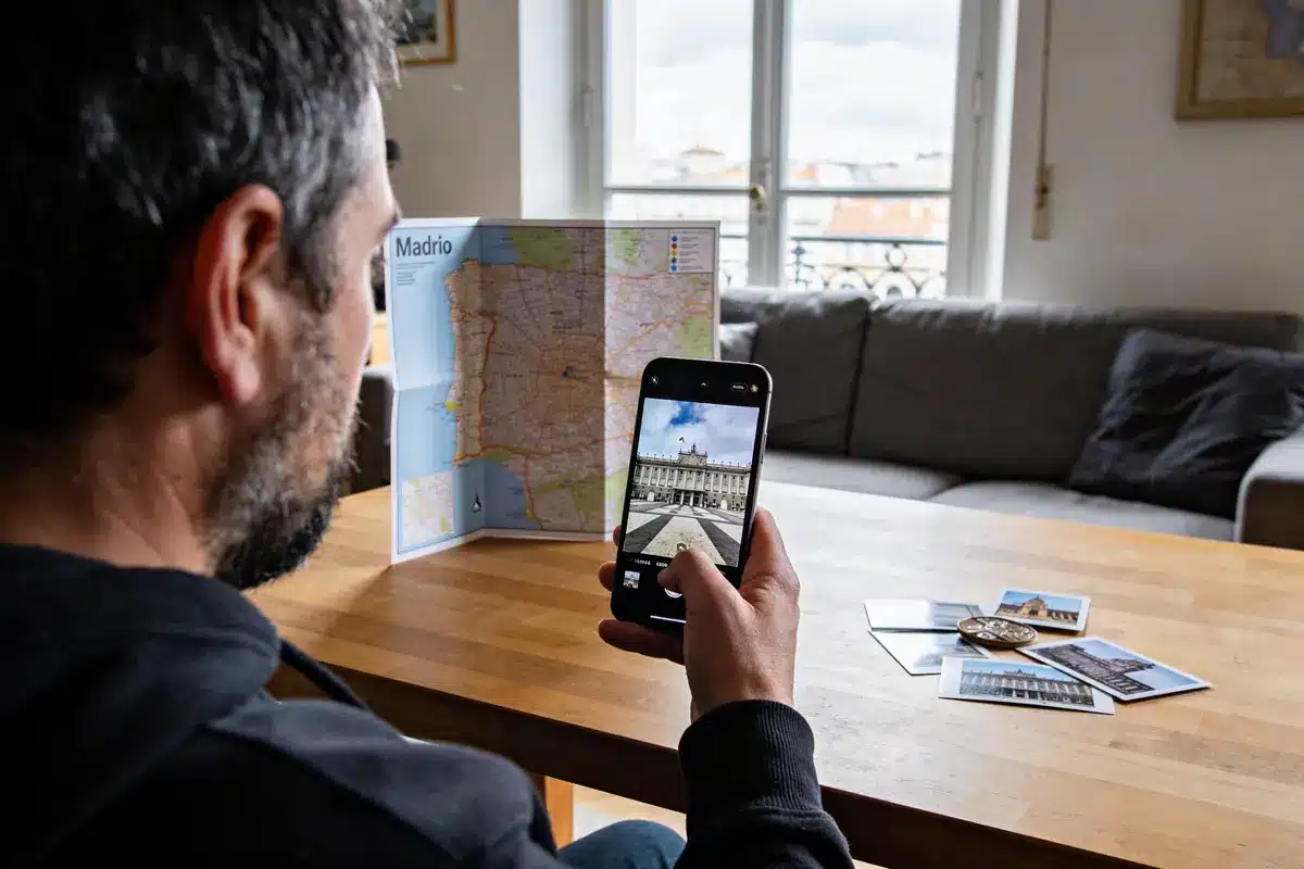 Un homme prend une photo d'une carte de Madrid avec son téléphone, posée sur une table.