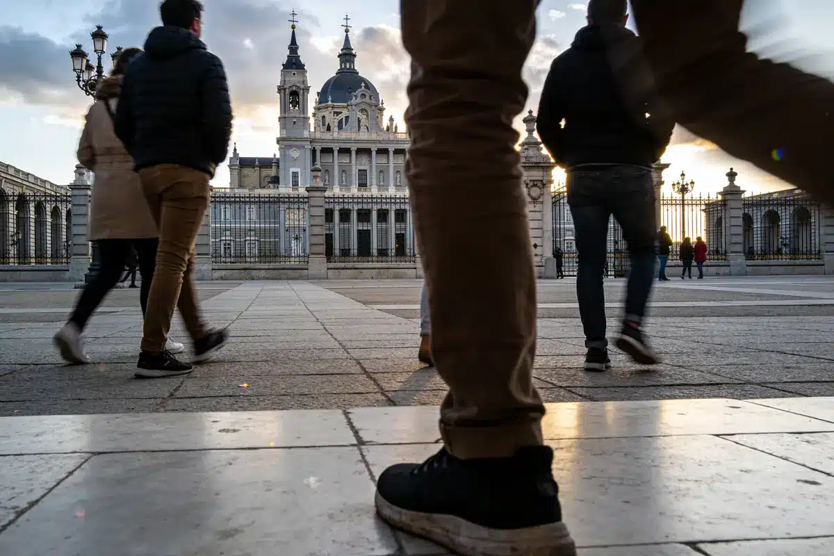 Personnes marchant près d'un bâtiment ancien avec dôme, éclairé par le soleil couchant.