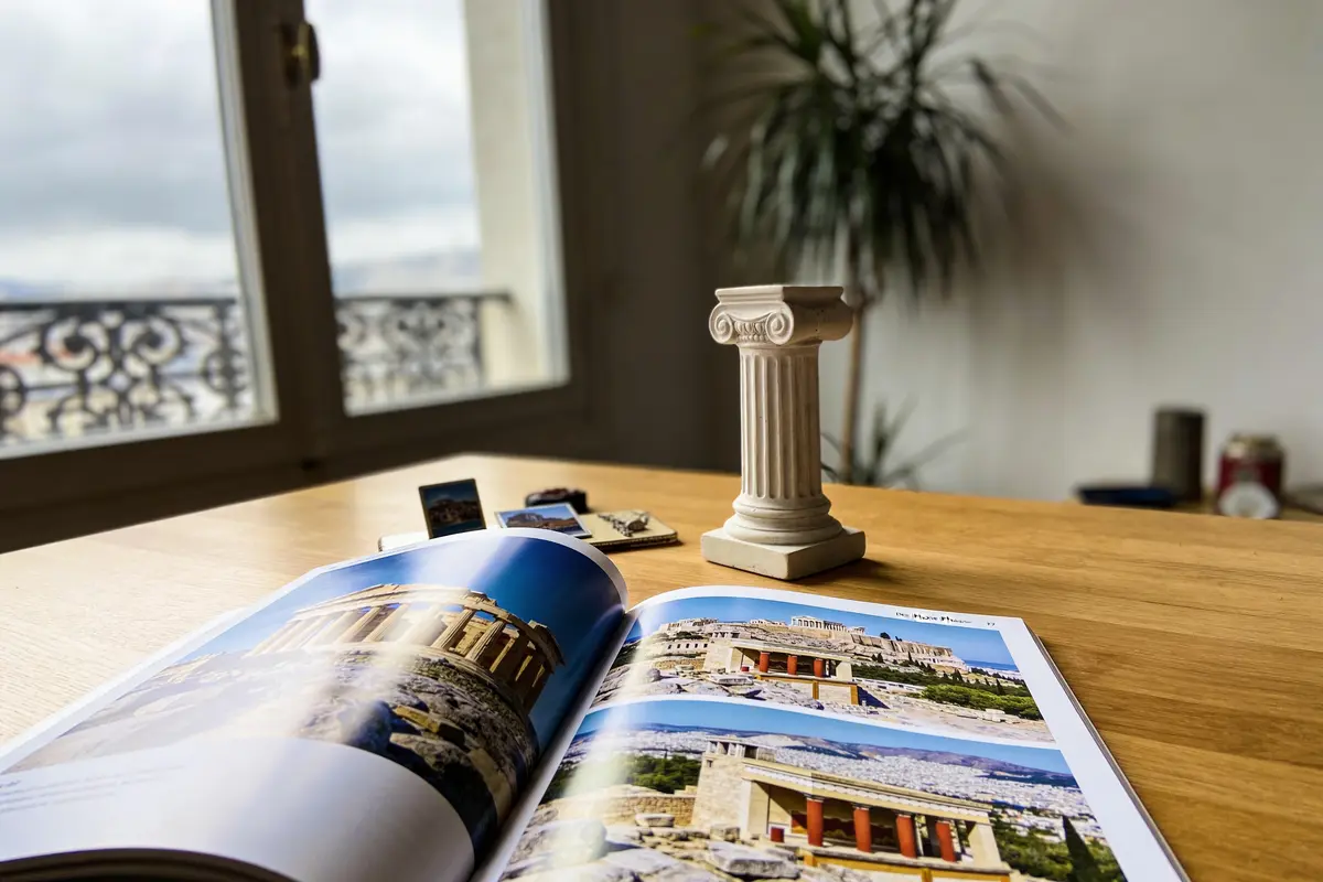 Magazine ouvert avec photos d'architecture grecque, miniature colonne ionique, intérieur avec fenêtre en arrière-plan.